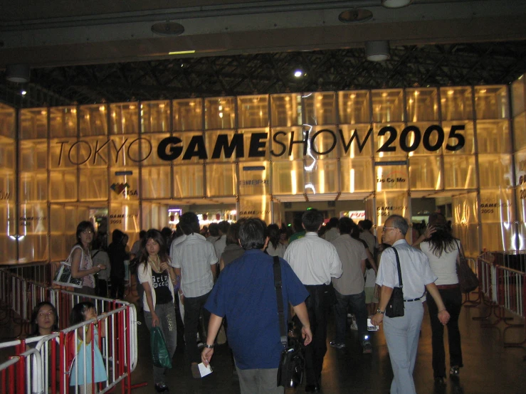 a group of people walk through a lobby inside a game show