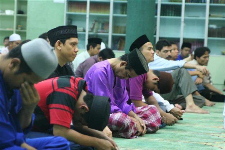 men and women sit on the floor in a line with the heads of their faces covered