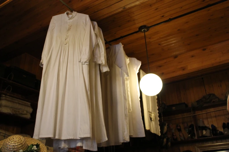 two dresses hanging from clothes racks in front of an illuminated light