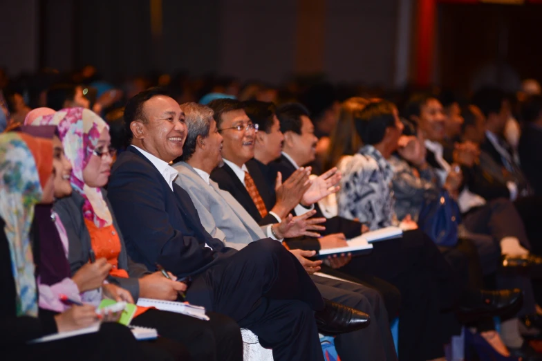 several people are seated in a row and clapping