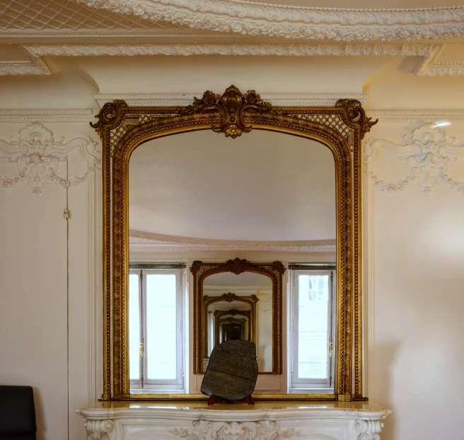 an ornately decorated gold mirror in the corner of a room