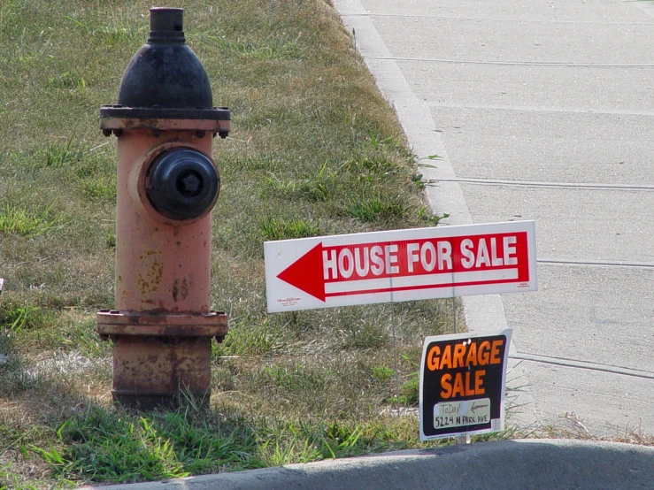 a sign posted by a fire hydrant next to a house for sale