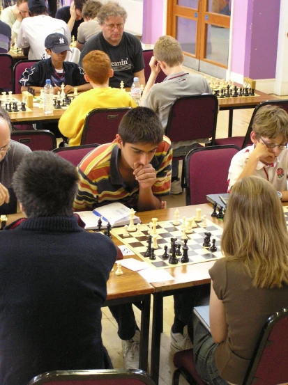 several people playing chess in a room filled with chairs