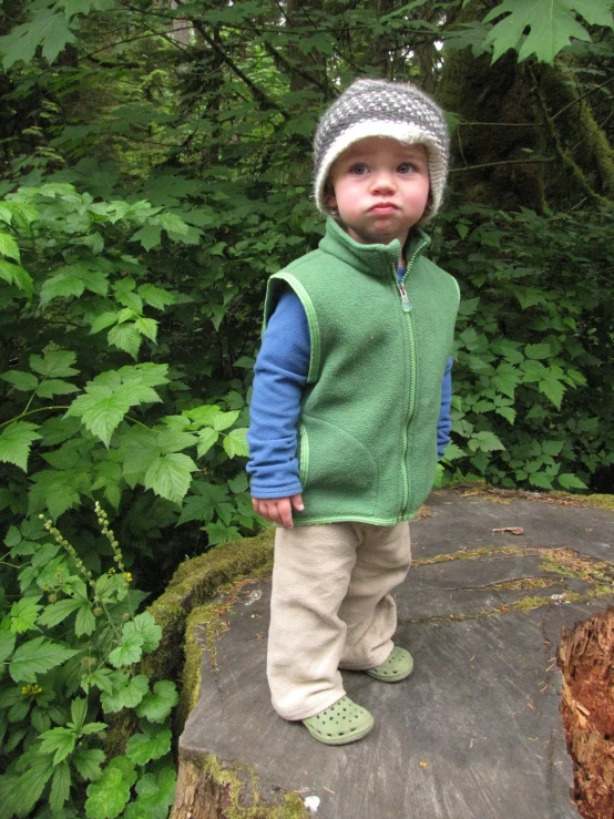 a toddler standing on a rock in the woods