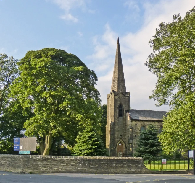 a cathedral with trees and a stone wall in the foreground