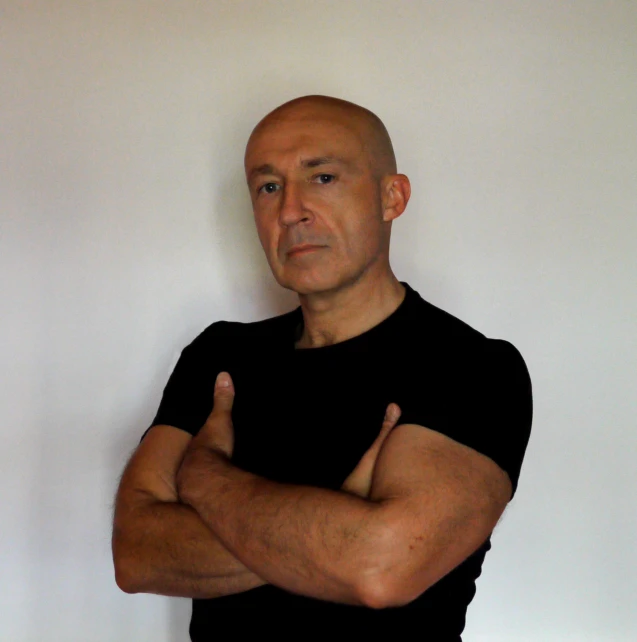 a bald man wearing a black t - shirt and a black jacket