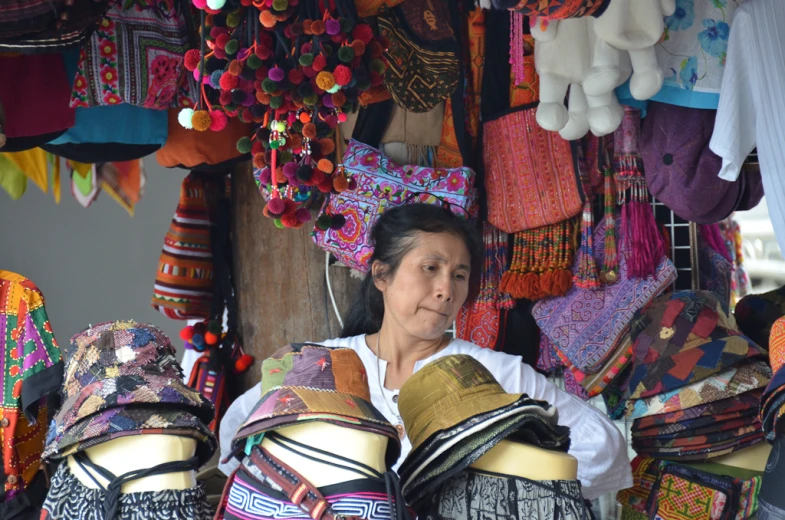 an asian woman standing in a colorful market looking at bags