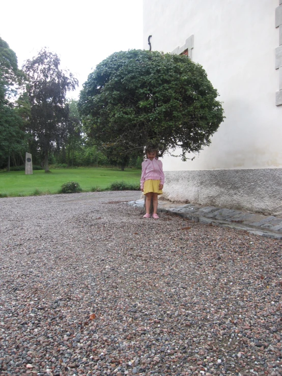 a little girl in yellow standing outside of a building