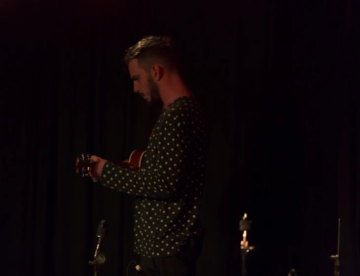 a man in black shirt standing in front of microphone and microphone stands next to microphone stand with microphone