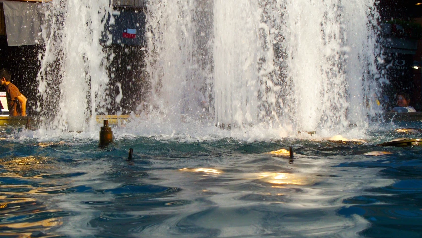 a fountain is filled with water as people sit near it