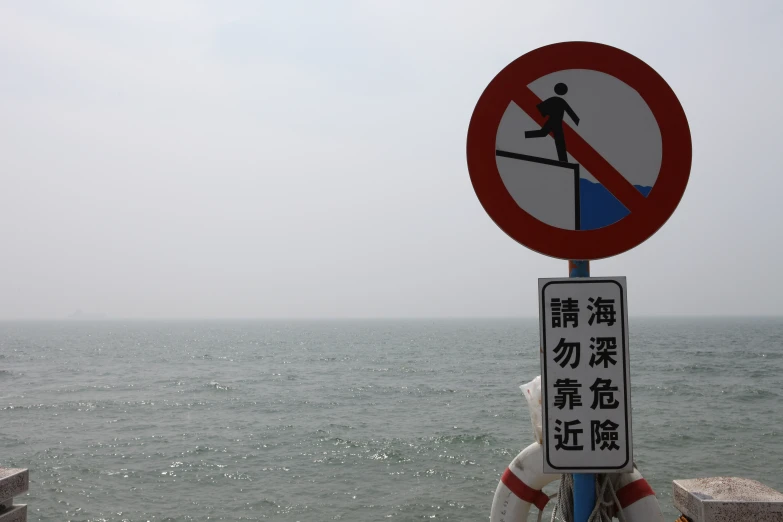 two signs with asian writing near a body of water