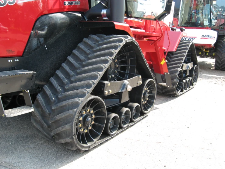 two tractors on the ground with their tracks folded over them