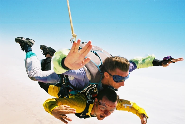 two men are hanging onto a rope above the beach