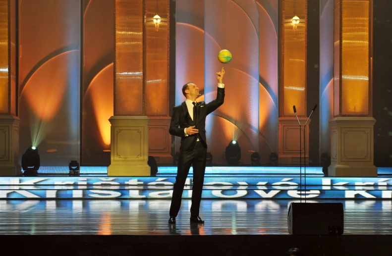 man in suit with ball at awards stage