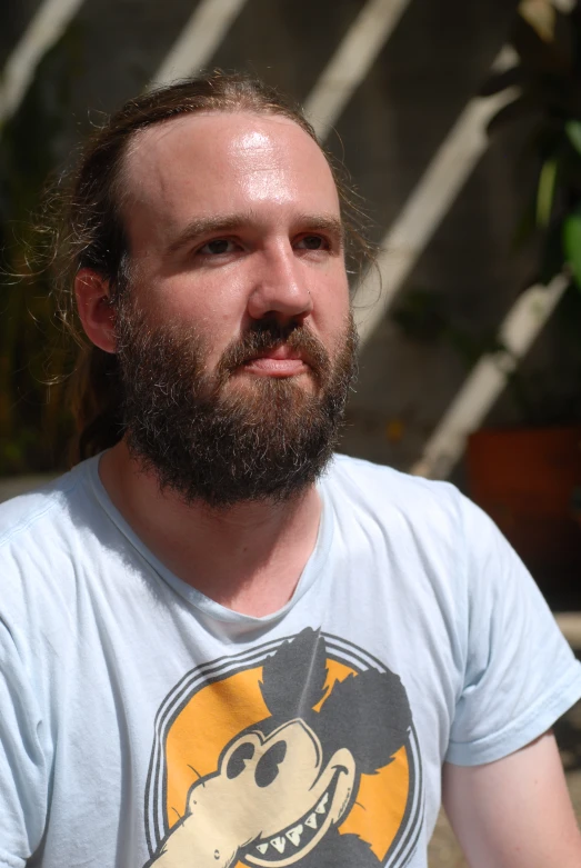 a man with long hair, wearing a shirt, has a smirk