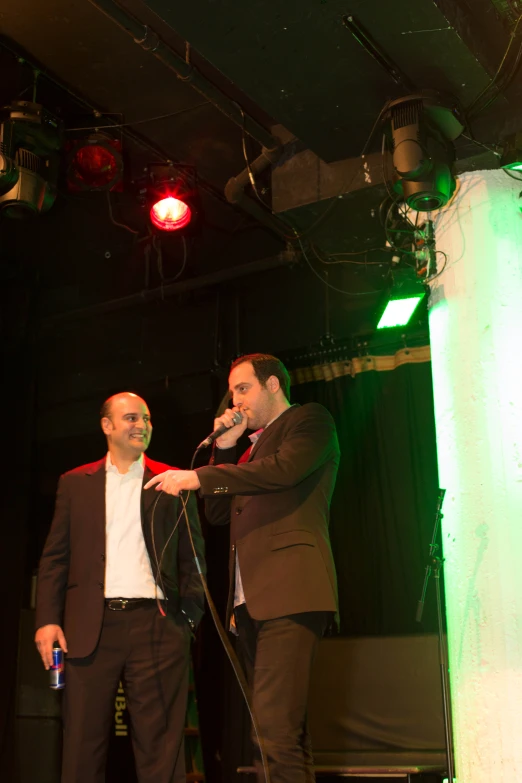 two men on stage holding microphones and talking