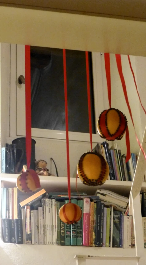 two pumpkins hanging from a shelf over books