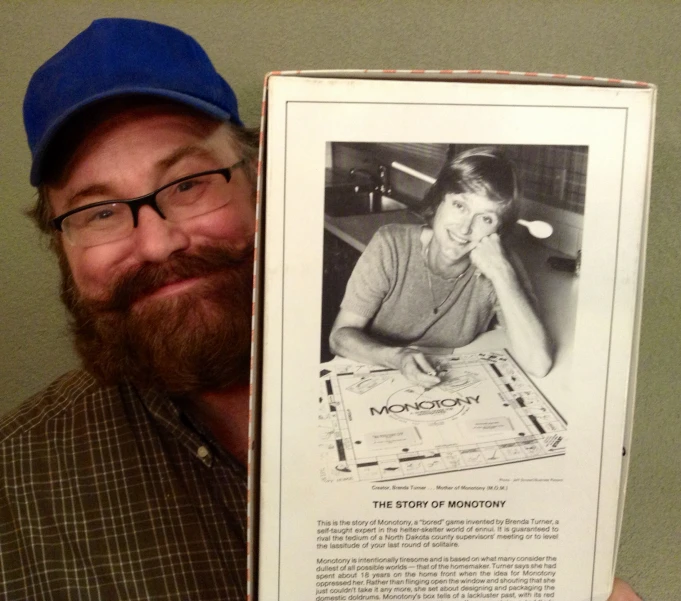 a man holds up his framed po and a vintage monopoly game