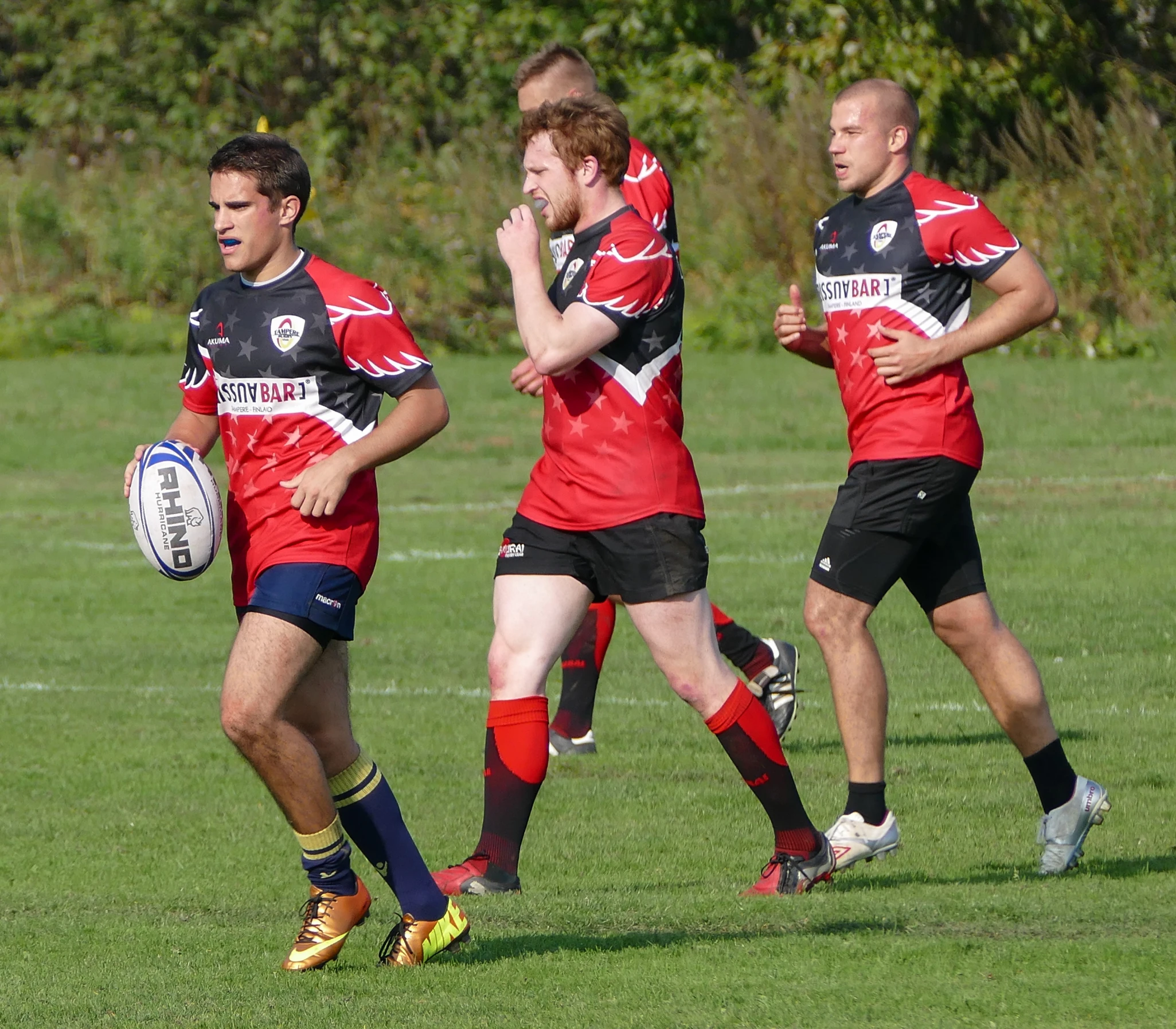 rugby players run as the opposing team wraps hands around