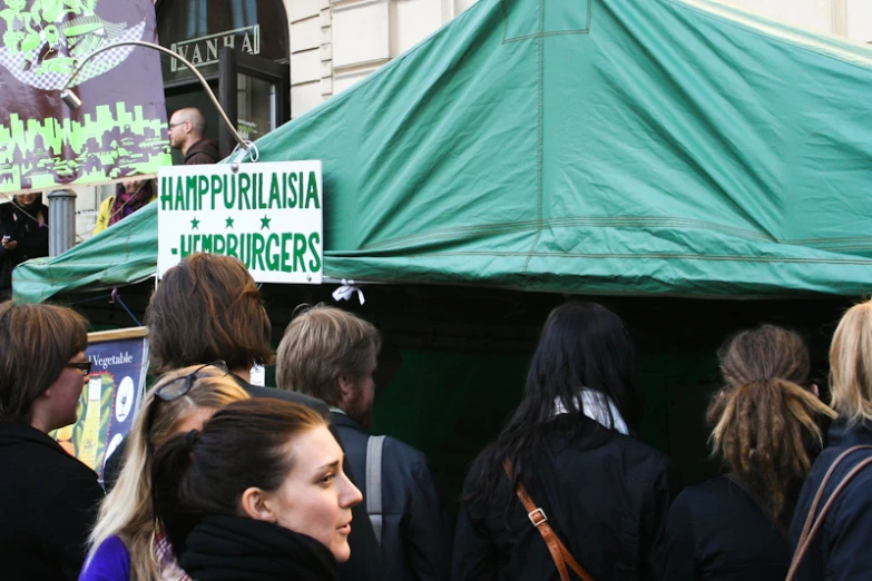 people gather near a green tent for a political rally