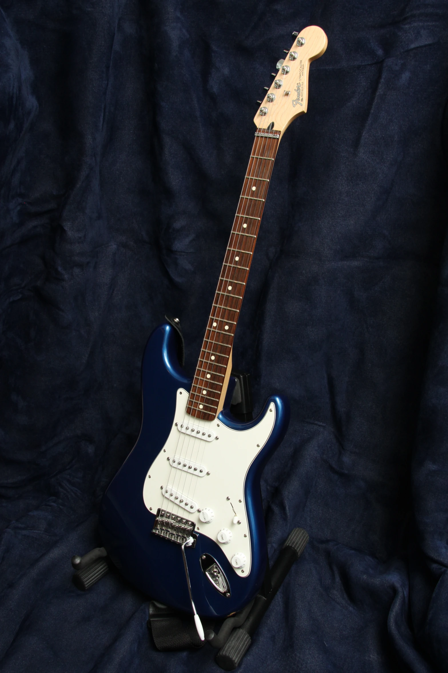 a blue electric guitar sitting on top of a dark background