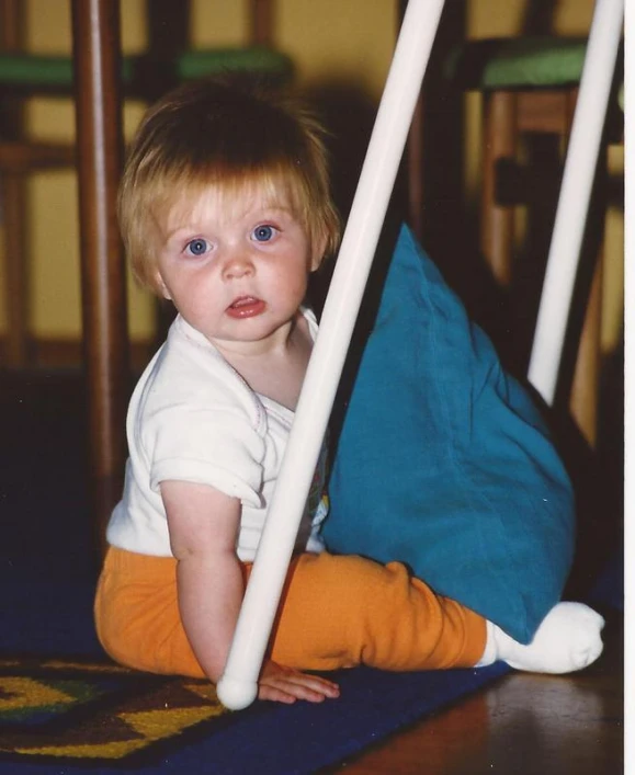 an older child sitting on the floor between two chairs