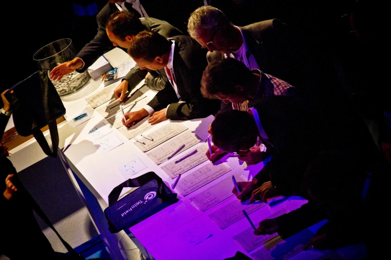 several men sitting at a table working with papers