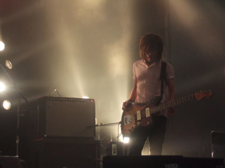 a young man is playing a guitar on stage