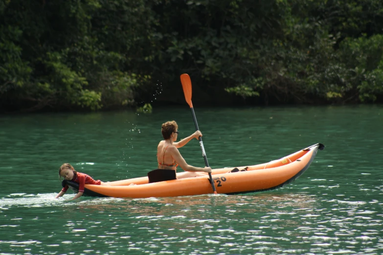 a woman and two s are in an orange kayak on the water