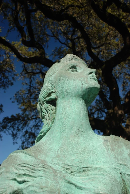 a statue is near a tree that has a blue sky in the background