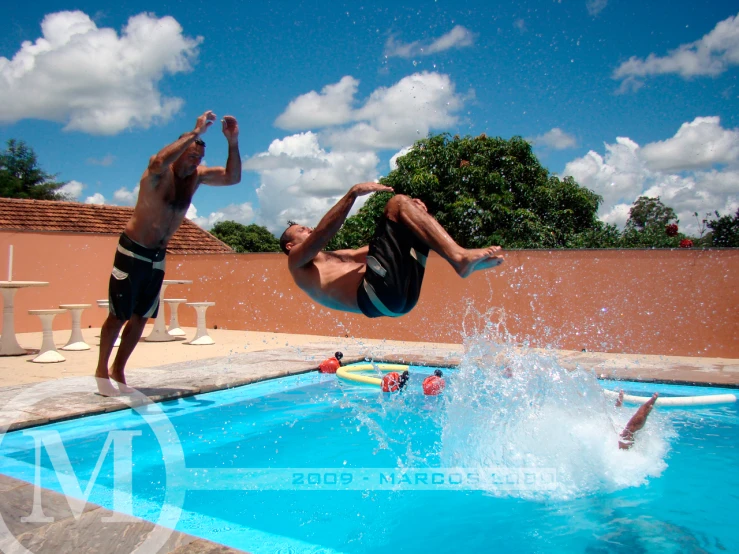 two guys doing tricks in the pool while others watch