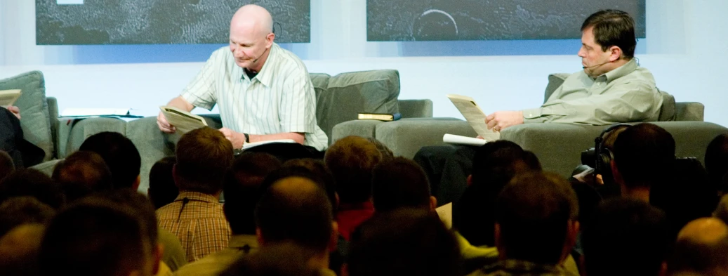 a couple of men sitting on top of chairs reading books