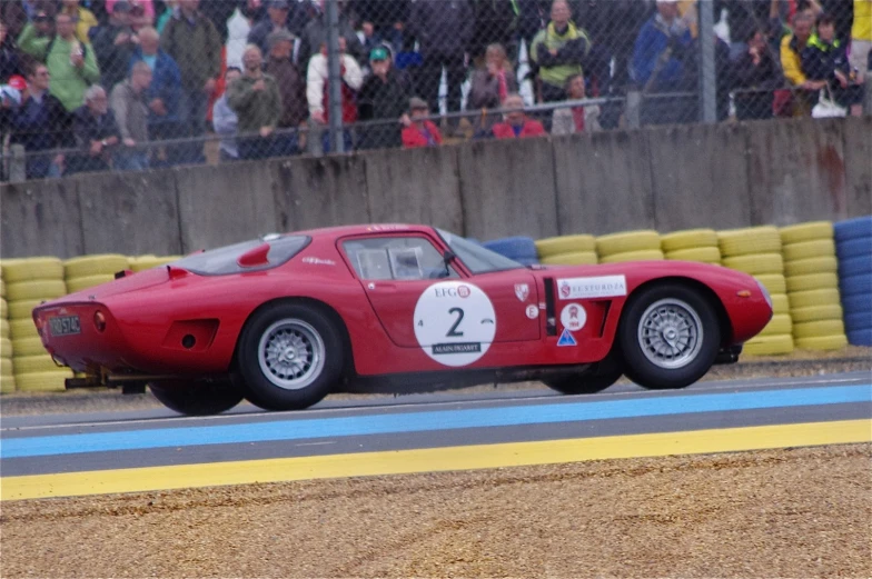 the car is driving past a crowd at the race track