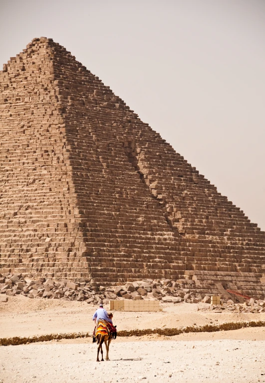 a person riding a horse past a pyramid