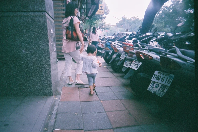 two women and a child are walking down a city sidewalk