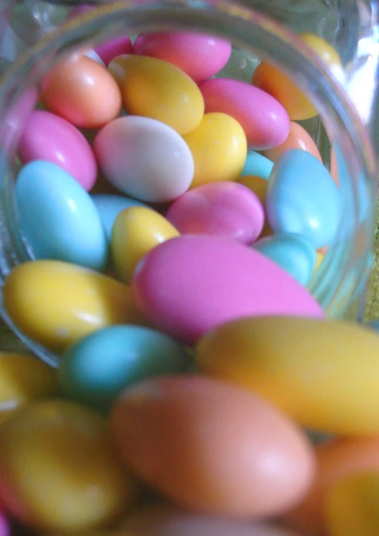 a jar filled with candy eggs, pastely colored