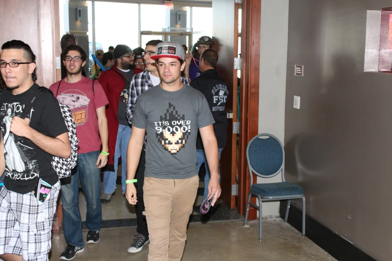 men standing in line in front of doors on a hall way