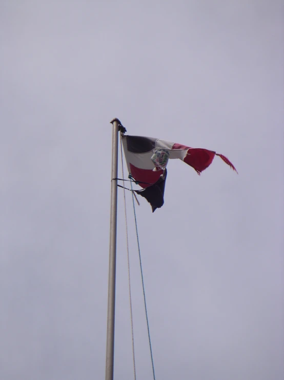 a flag flies high in the air with another flag blowing behind it