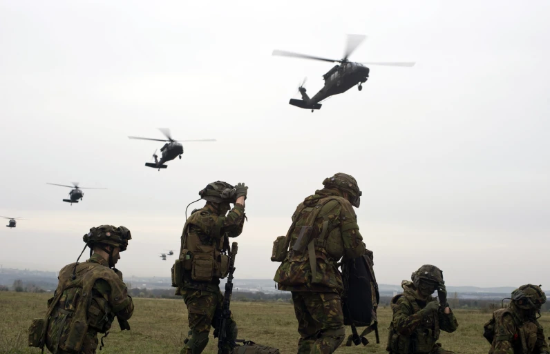 some soldiers watch two airplanes flying by