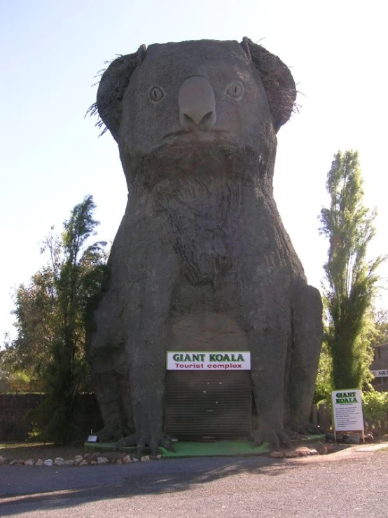 a large giant fake bear standing next to a sign