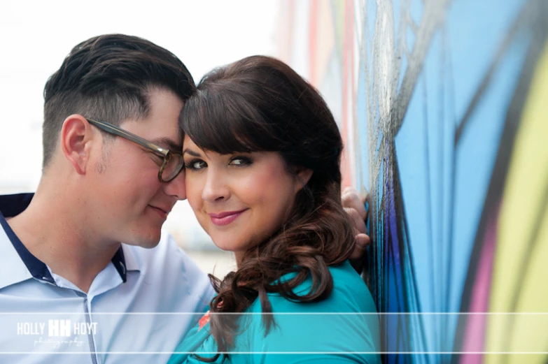 a couple kissing and leaning against a wall