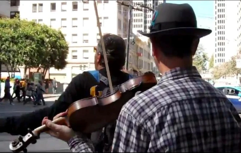 two people playing music while riding bicycles down a busy street