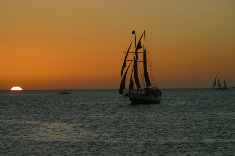 a boat sailing on the ocean during sunset