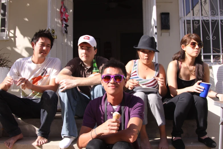 several people sit on a bench on the porch of a building