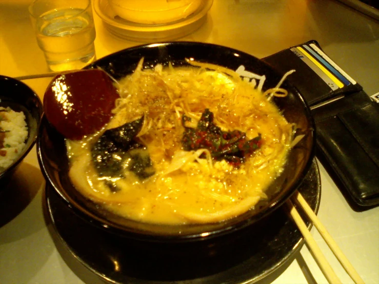 a bowl with food, rice and chopsticks on the side