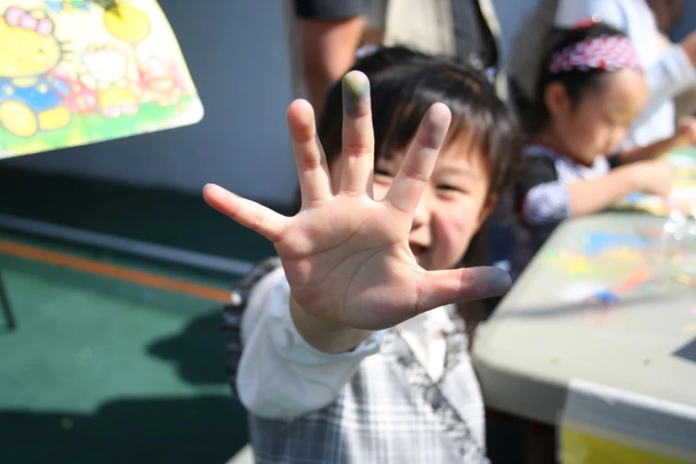 a child standing in front of a table while making an okay sign