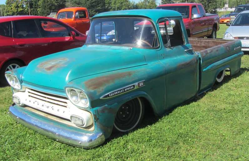 an old green truck is sitting in the grass