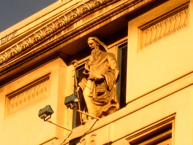 a statue of a man with a hat stands atop an office building