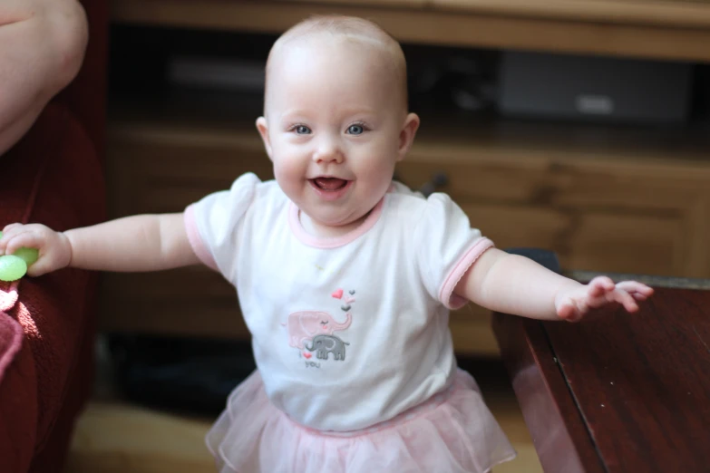 a baby girl is sitting next to a table