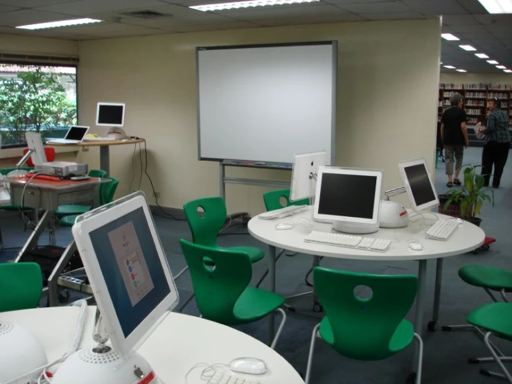 a classroom with a laptop, monitor and laptop on the table